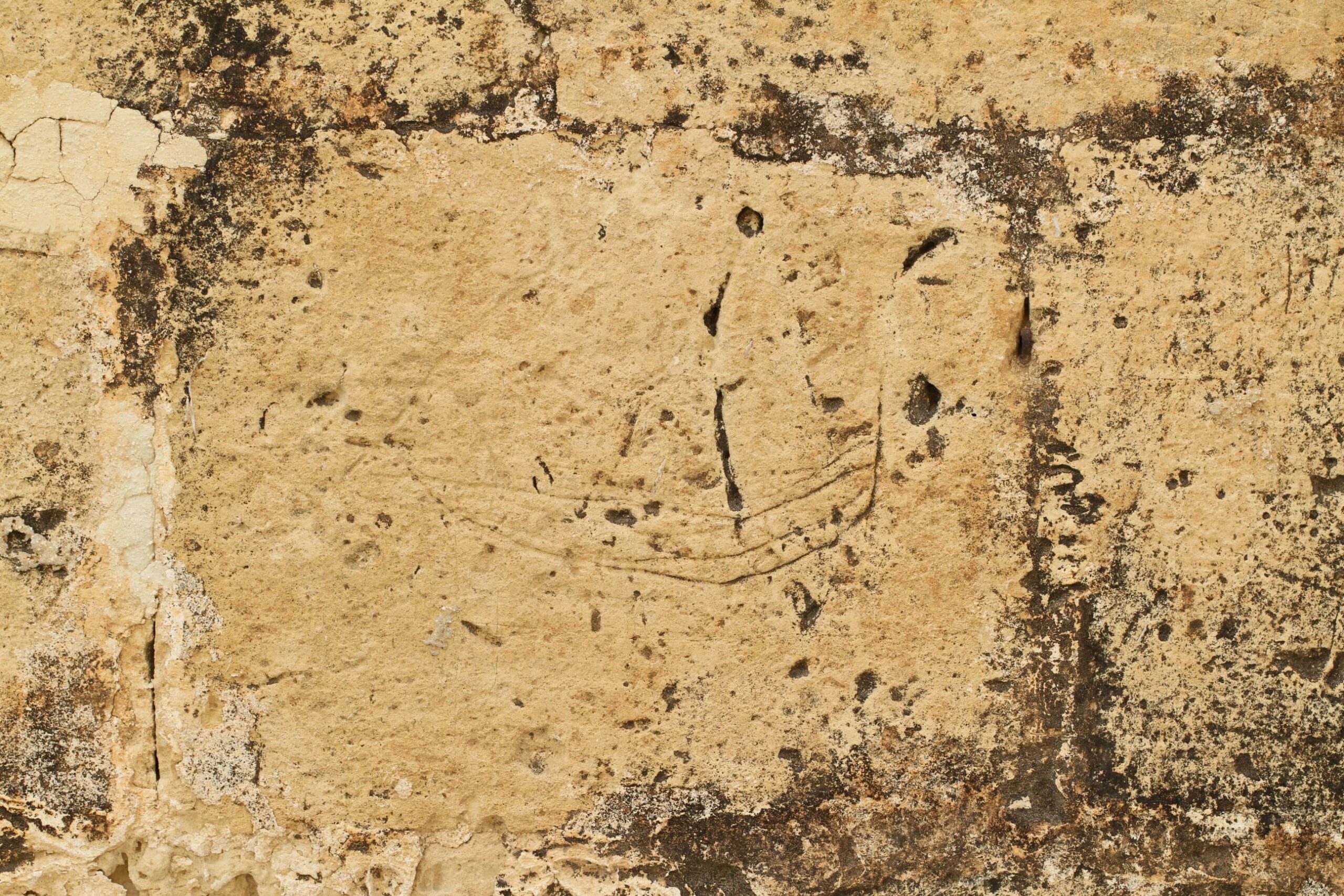 A simple ship graffito showing a hull and two lateen sails. The sails are fast disappearing from view.